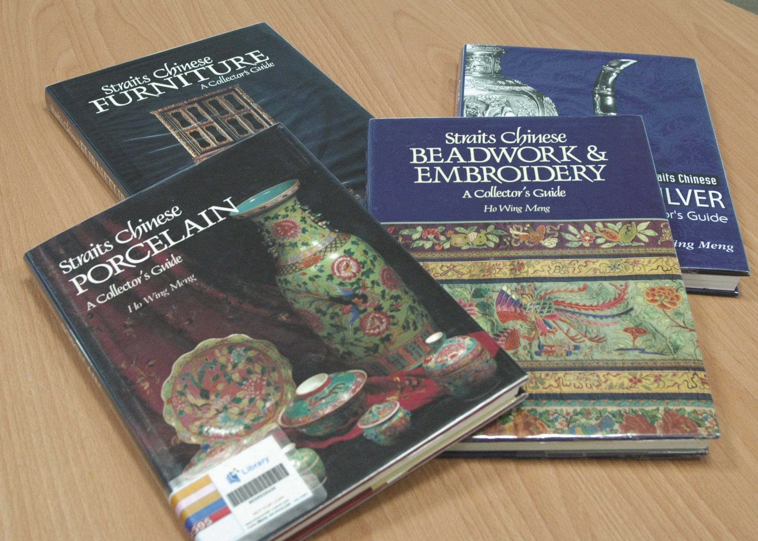 Four books titled "Straits Chinese Furniture," "Porcelain," "Beadwork & Embroidery," and "Silver" are on a wooden table.